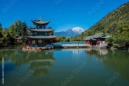 Black Dragon Pool to the Five Phoenix Tower. In the background is Jade Dragon Snow Mountain. The Old Town of Lijiang is located in Lijiang City, Yunnan, China.