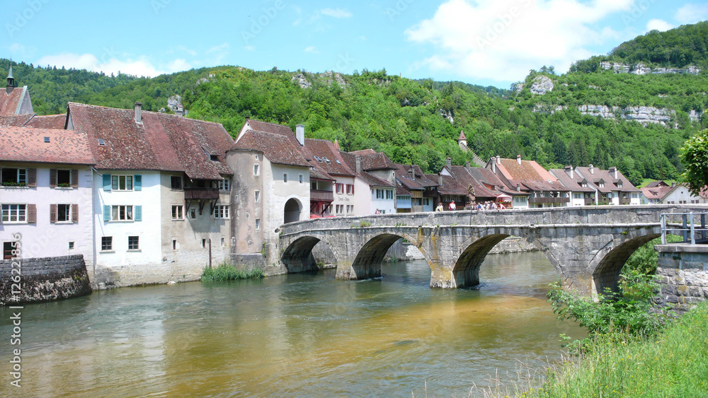 small medieval village with an old stone bridge over a river in Switzerland