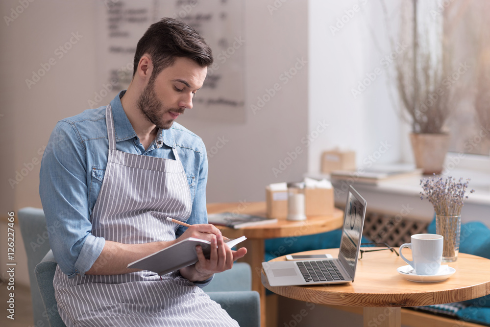 Ambitious man sitting on an armchair and making notes. Ambitious man sitting on an armchair and making notes.