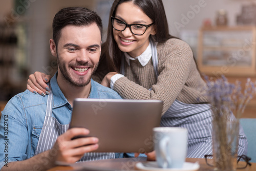 Delighted couple smiling and using tablet.