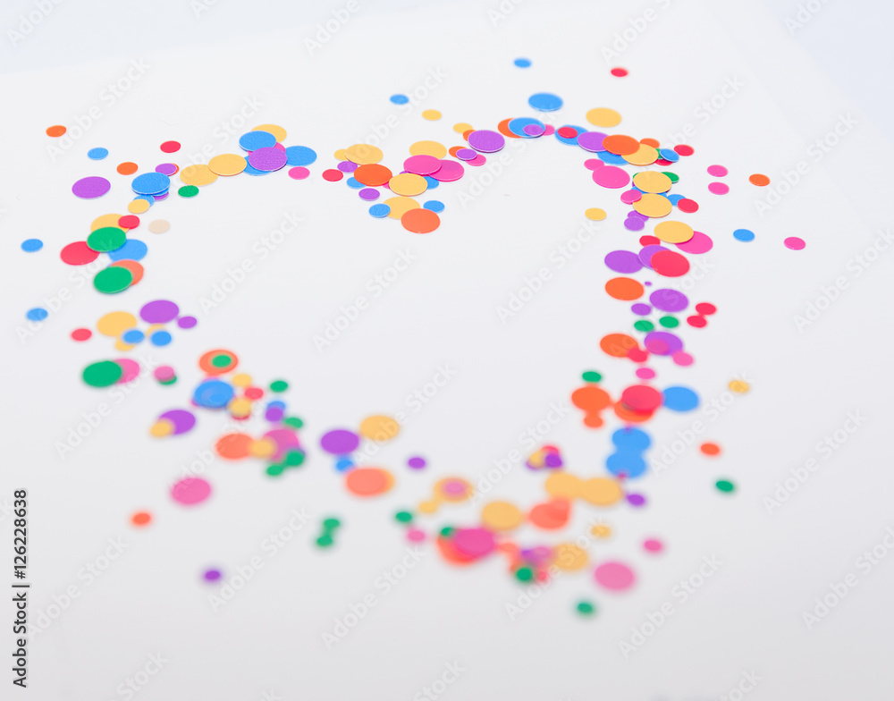 Heart symbol made of colorful confetti on white background