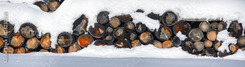 The logs woodpile in the snow in winter. Rural winter scene. 