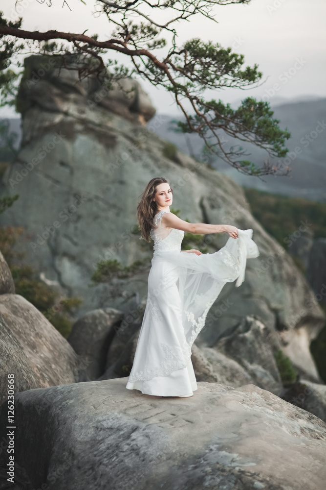 Gorgeous bride in elegant dress holding bouquet posing near forest Gorgeous bride in elegant dress holding bouquet posing near forest