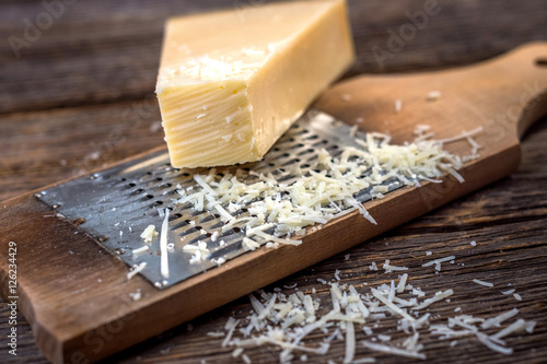 Grated parmesan cheese and  grater on wooden background