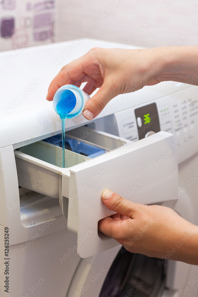 She pours the liquid powder in washing machine She pours the liquid powder in washing machine