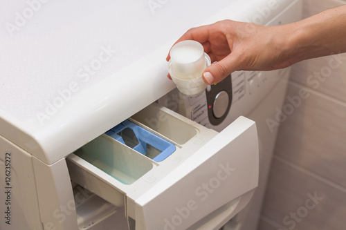 The girl pours detergent into the compartment with rinse aid