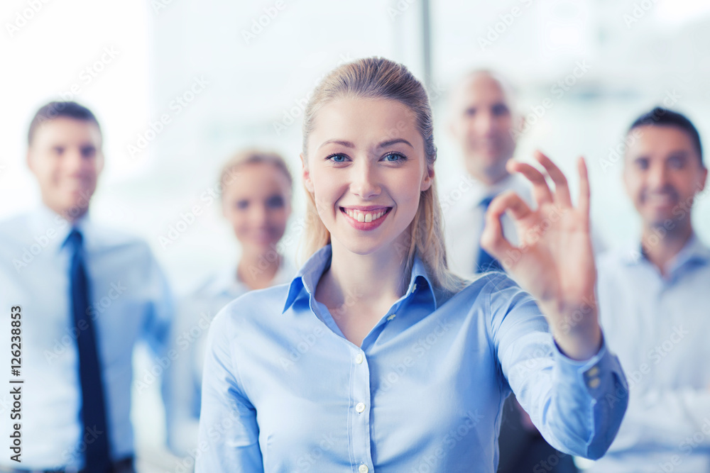 smiling businesswoman showing ok sign in office smiling businesswoman showing ok sign in office