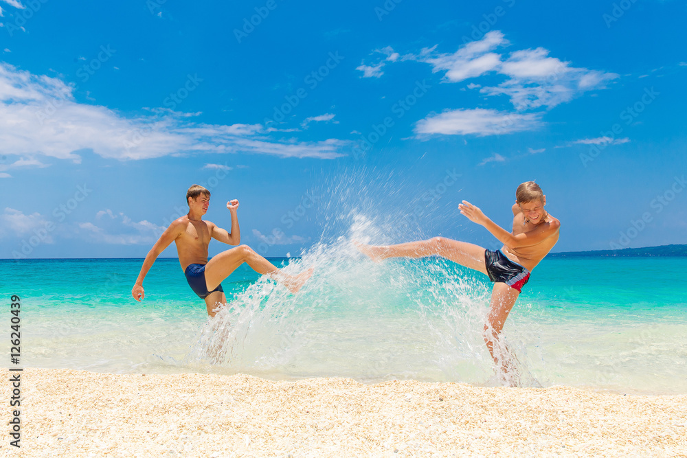 Happy teen boys having fun on the tropical beach. Summer vacatio Happy teen boys having fun on the tropical beach. Summer vacatio