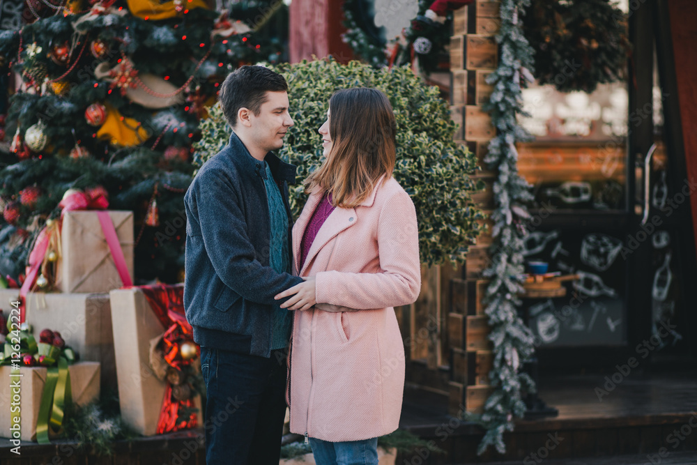 Obraz premium Happy couple in warm clothes posing on a Christmas market. Holiday mood
