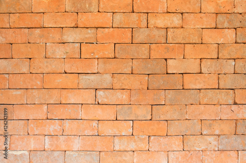 the old and dirty orange brick wall in warm or hot color tone style with black stain for background texture