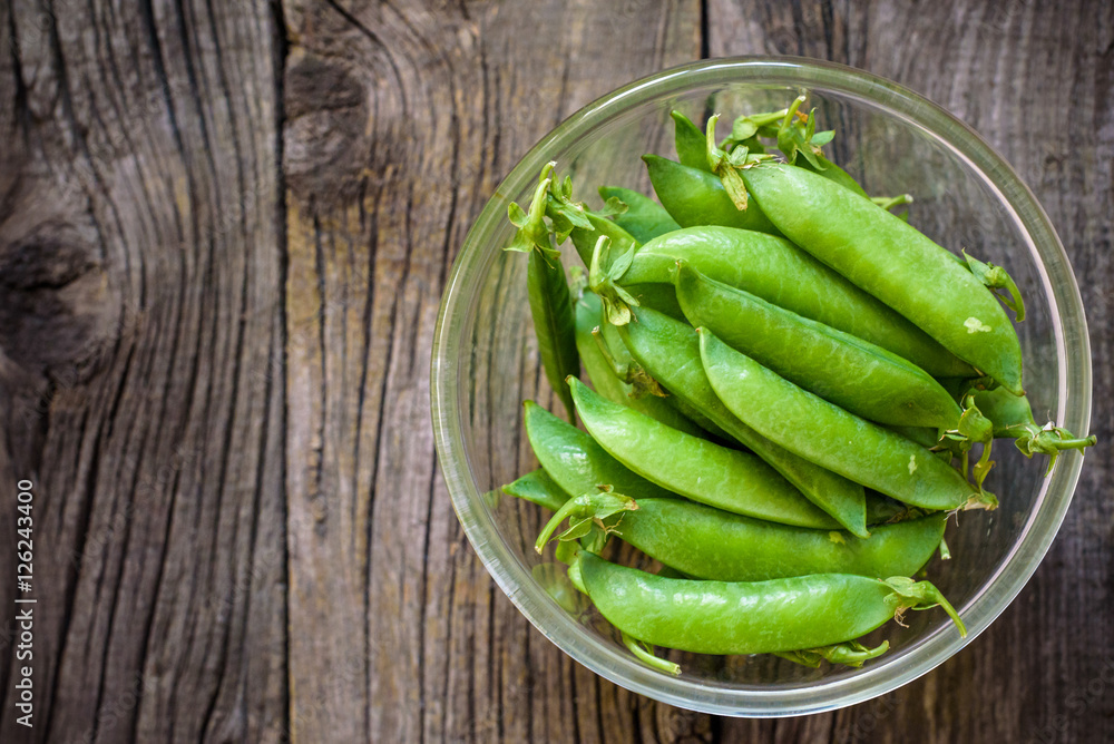 Fresh, young unpeeled green peas in a glass plate Fresh, young unpeeled green peas in a glass plate