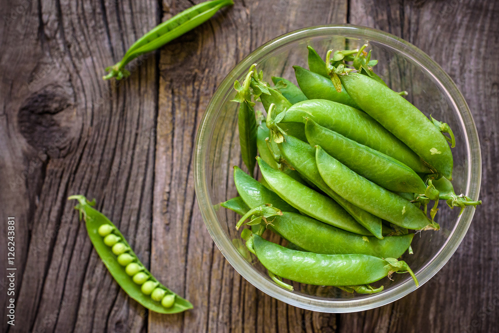 Fresh, young unpeeled green peas in a glass plate Fresh, young unpeeled green peas in a glass plate