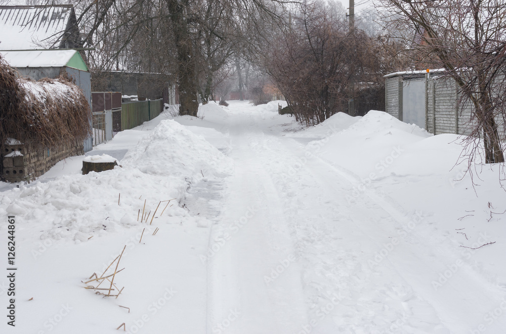 Naklejka premium Snow-covered small street of the Dnepropetrovsk city's suburb after snowfall and icing over