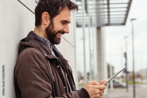 Outdoor portrait of modern young man with digital tablet in the street.