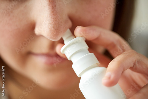 close up of sick woman using nasal spray photo