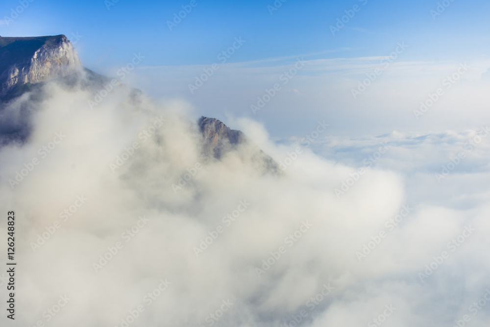Picturesque view of a layer of white clouds below the mountain peak
