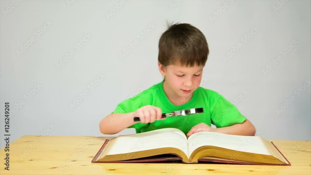 Little boy reading the book with magnifier Little boy reading the book with magnifier