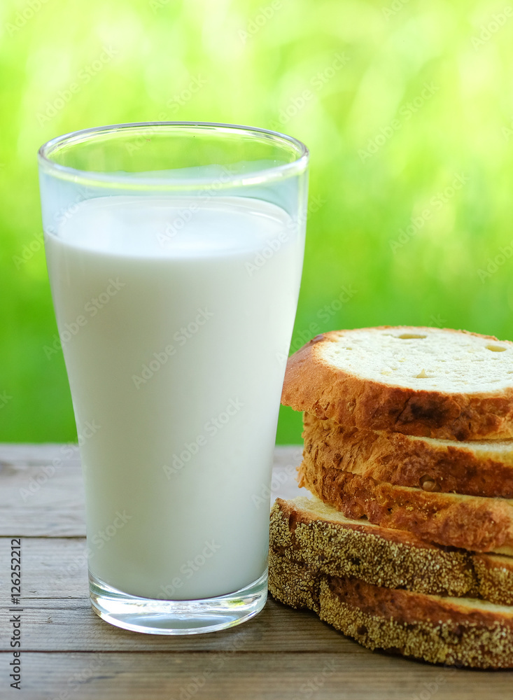 Bread cut pieces with milk glass on wooden table,green blurred Bread cut pieces with milk glass on wooden table,green blurred