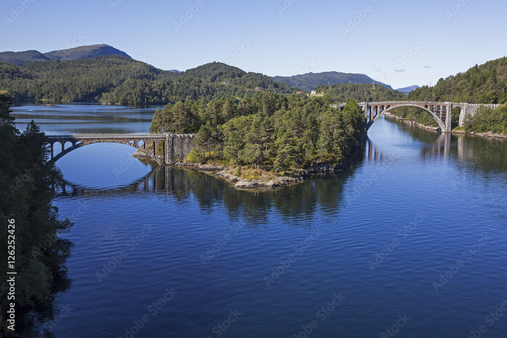 Obraz premium Old bridges to the wooded island in the middle of the bay, Norway