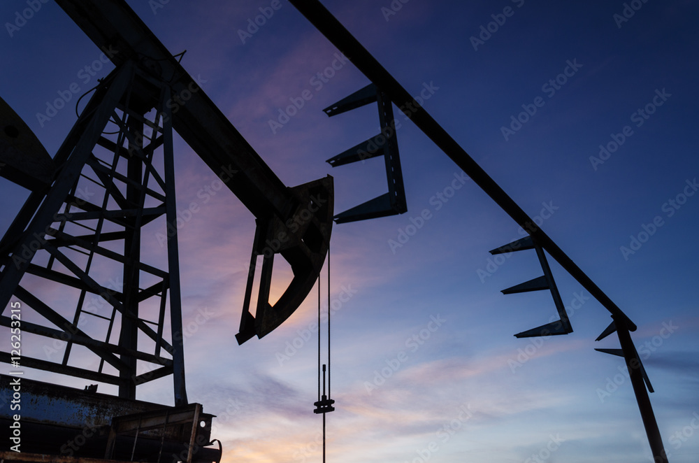 Oil pump and pipeline silhouette during sunset at the oilfield.  Oil and gas concept.