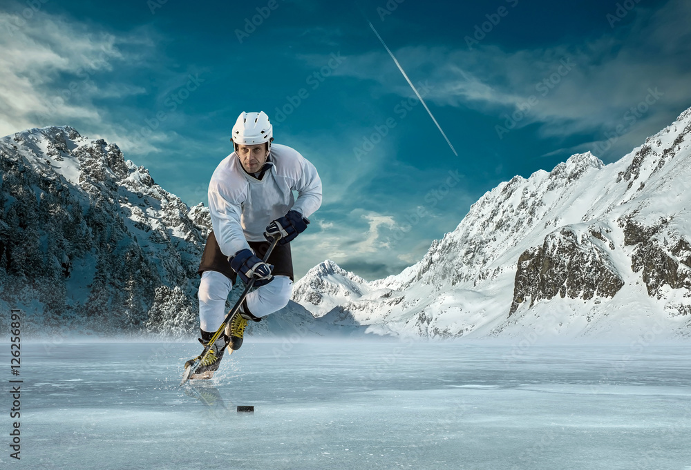 Fototapeta premium Ice hockey player in action outdoor around mountains