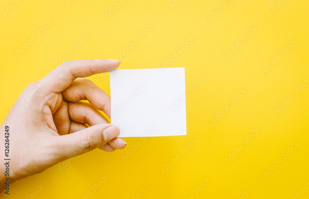 Hand holding paper on yellow background Hand holding paper on yellow background