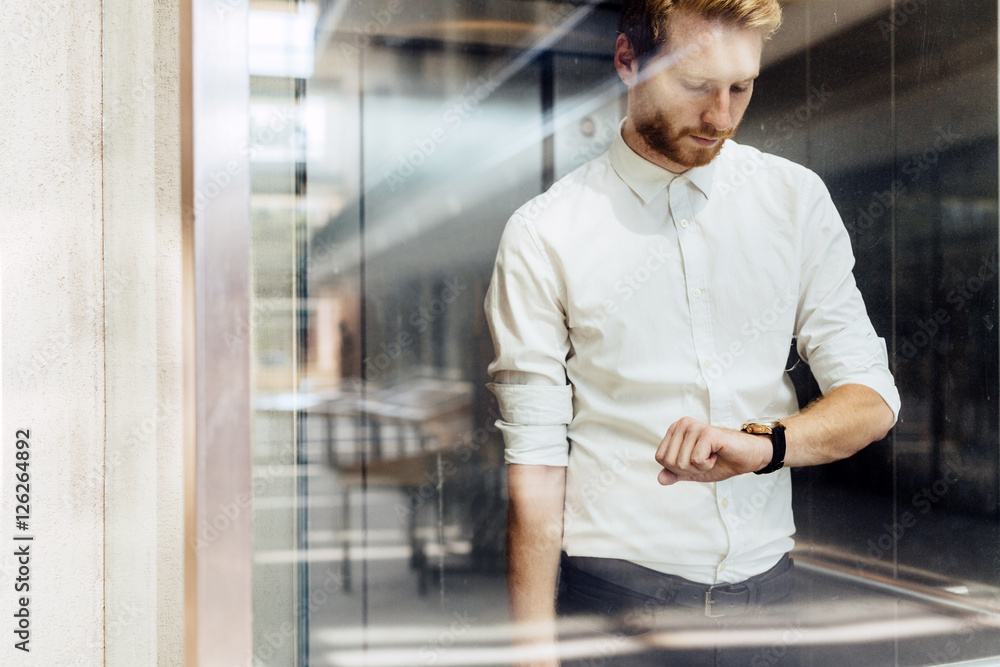 Businessman checking watch while standing in elevator Businessman checking watch while standing in elevator