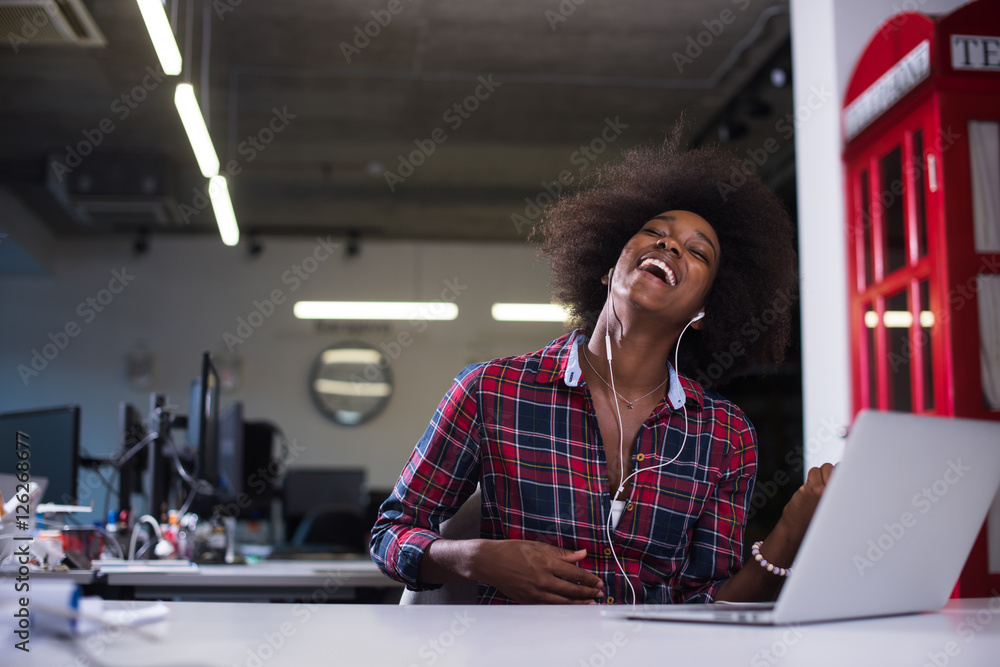 black woman in modern office speeking on phone over earphones