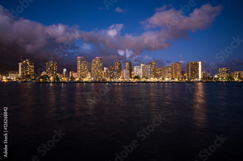 Skycraper light up at night with waterfront © littlestocker