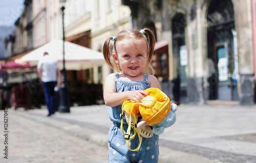 Nice girl with yellow backpack walking city