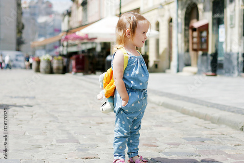Beautiful girl with yellow backpack walking city © Yuliia