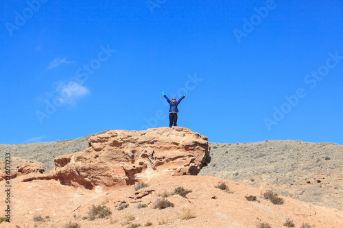 Happy woman standing on the top of the hill with raised hands and enjoy the view 