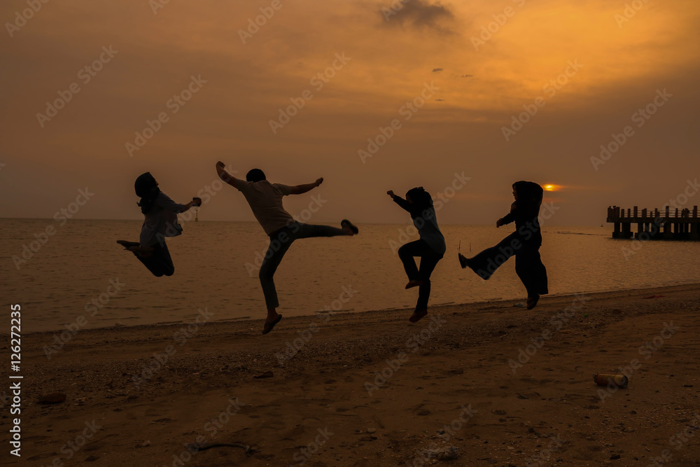 Fototapeta premium silhouette of friends jumping in sunset