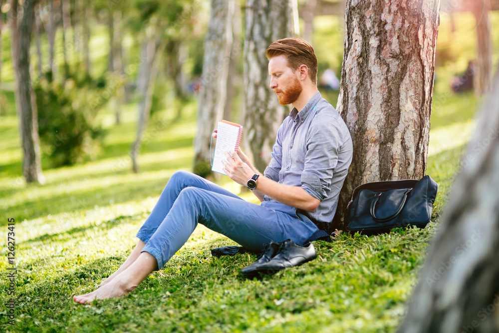 Handsome student reading in nature