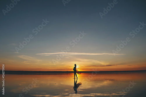 Силуэт беременной женщины на берегу моря на закате