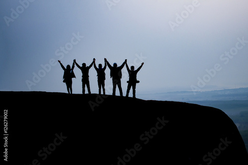 silhouette group people hold hands together on the top of the mountain