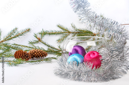 christmas balls in glass vase among tinsel on white background