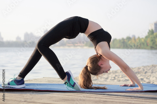 Sporty flexible girl stretches at bridge yoga exercise outdoor