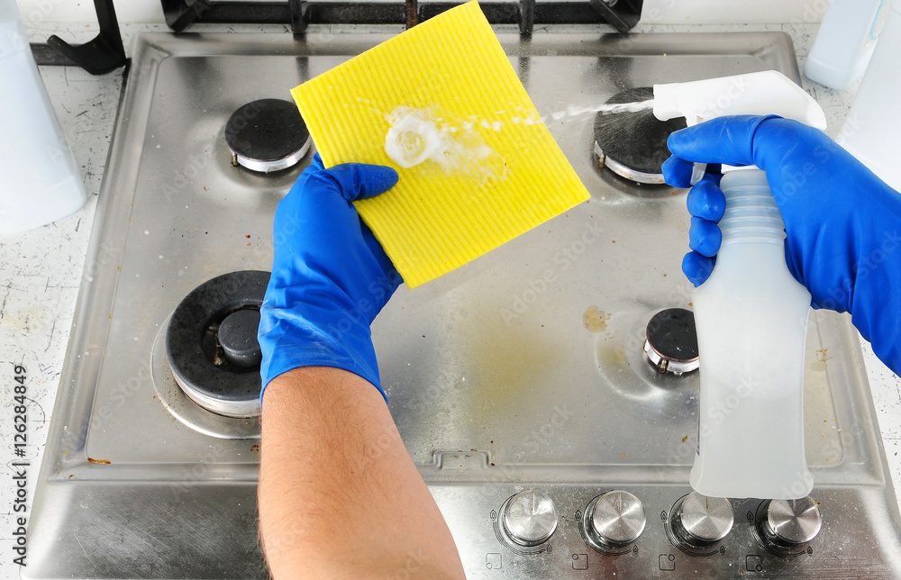 Cleaner sprinkles detergent on a cloth for cleaning the kitchen. Man