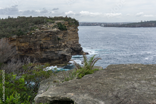 Steep rocky coast of Australia and the blue sea waves breaking on the rocks, the entrance to Sydney Harbour, Sydney