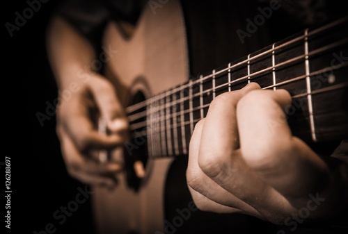 Close up hands on the strings of a guitar