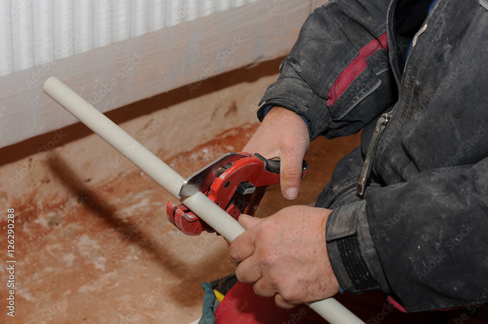 Plumber worker with scissors cuts the tube. cutting metal-plastic pipe by  special red scissors. Plumber hands working with grey pipe on blurred  background. plumbing pipes. individual heating system. Photos | Adobe Stock