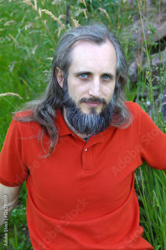 bearded man sittingin green field on sunny day, potrait photo