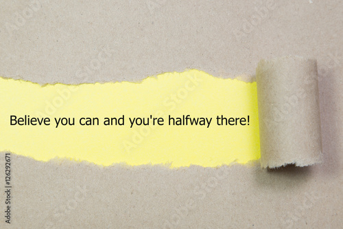 The text Believe you can and you're halfway there, appearing behind torn brown paper. Motivational quote.
