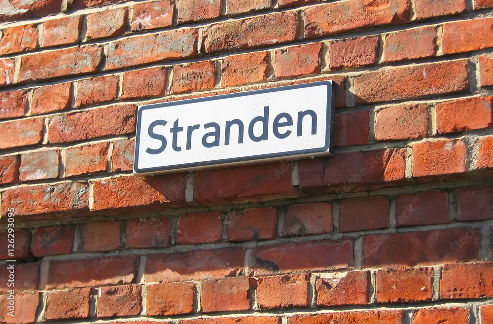 Oslo. Norway. The street name plate on the brick wall. Stranden is name of waterfront promenade in Aker Brygge District, popular touristic place in historical part of the city. Oslo. Norway. The street name plate on the brick wall. Stranden is name of waterfront promenade in Aker Brygge District, popular touristic place in historical part of the city.