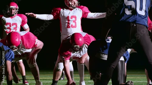 football teams on the line of scrimmage and quarterback looks over the field