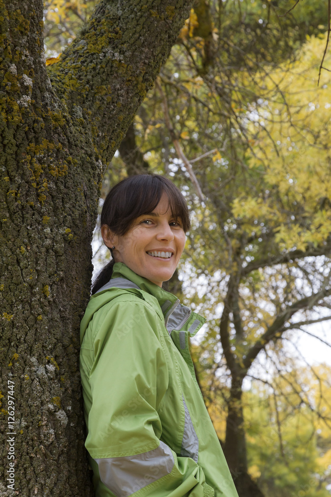 Woman sitting on a park bench with yellow leaves falling from trees Woman sitting on a park bench with yellow leaves falling from trees