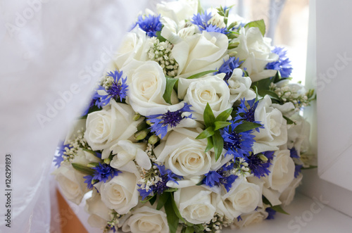 beautiful bouquet of white roses and cornflowers, rests on the w