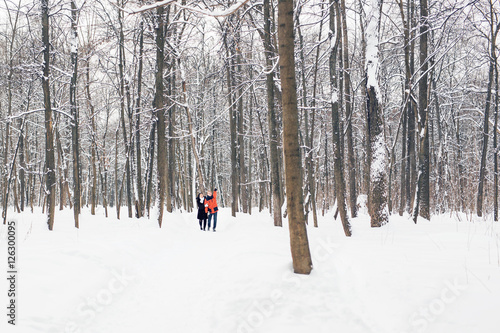 happy couple walking through a snowy forest in winter © satura_