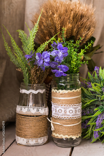 Rustic still life: dried flowers bunch and vases on vintage wooden background.